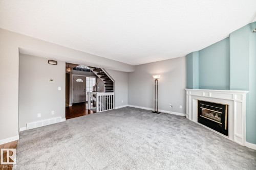 Spacious living area featuring light gray walls and plush gray carpeting - 2709 124 Street, Edmonton, AB - Indoor With Fireplace