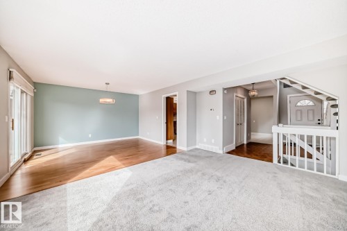 Open-concept living area featuring light gray carpeting and wood-finish flooring - 2709 124 Street, Edmonton, AB - Indoor Photo Showing Other Room