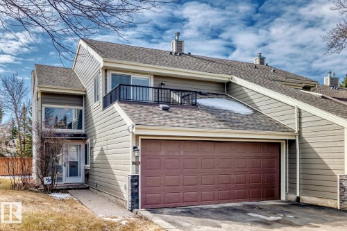 Multi-level residence featuring horizontal siding, an integrated single-car garage with a brown panel door, and an upper-level balcony with black railing - 2709 124 Street, Edmonton, AB - Outdoor With Exterior