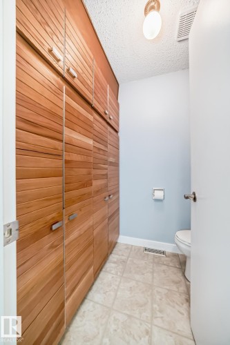 Built-in wood-finish cabinetry featuring horizontal slat details and silver-tone hardware - 2709 124 Street, Edmonton, AB - Indoor Photo Showing Bathroom
