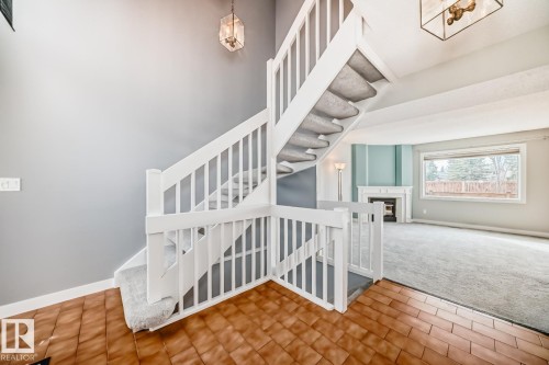 Two-story entryway with wood-finish tile flooring and a carpeted staircase featuring white railings - 2709 124 Street, Edmonton, AB - Indoor Photo Showing Other Room
