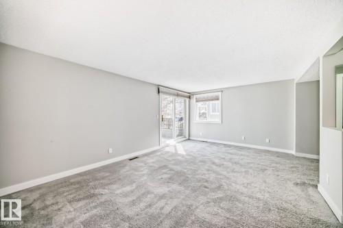 Spacious room with light gray walls, textured gray carpeting, and white baseboards - 2709 124 Street, Edmonton, AB - Indoor Photo Showing Other Room