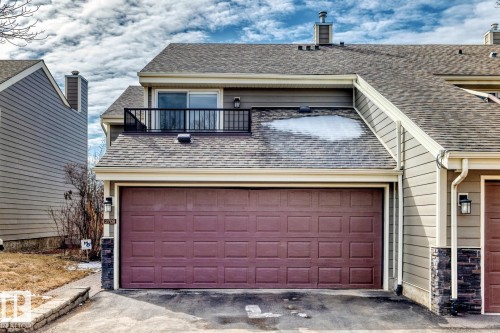 Two-car garage with a paneled door, stone veneer accents, and an upper-level balcony with a black metal railing - 2709 124 Street, Edmonton, AB - Outdoor With Exterior