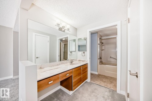 Double vanity with integrated sinks, stone-finish countertop, and wood-finish cabinetry - 2709 124 Street, Edmonton, AB - Indoor Photo Showing Bathroom