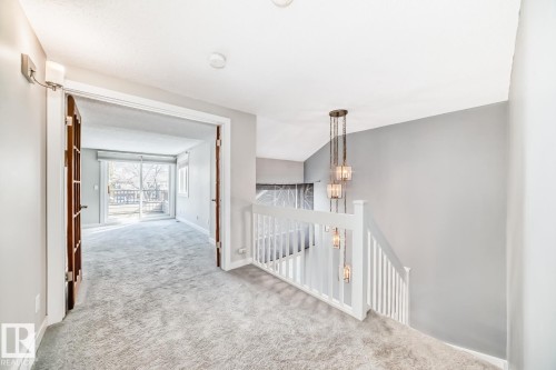 Upper-level landing featuring light gray carpeting and a contemporary multi-pendant chandelier - 2709 124 Street, Edmonton, AB - Indoor Photo Showing Other Room