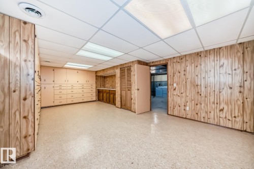 Lower level space with extensive built-in cabinetry, wood paneling, and drop ceiling with recessed lighting - 2709 124 Street, Edmonton, AB - Indoor Photo Showing Other Room
