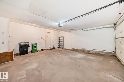 Spacious garage featuring a concrete floor, overhead lighting, garage door opener, and interior access door - 2709 124 Street, Edmonton, AB - Indoor Photo Showing Garage