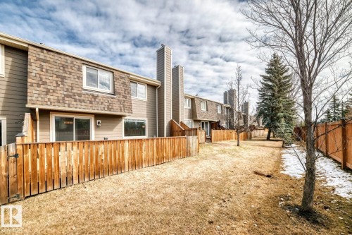 Rear exterior of a townhouse featuring horizontal siding and a gambrel-style roof with shingle siding - 2709 124 Street, Edmonton, AB - Outdoor