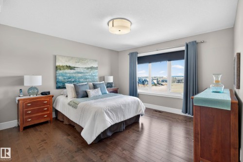 Bedroom featuring wood-finish flooring, light grey painted walls, a flush-mount ceiling light, and a large window with white trim - 2086 Redtail Common, Edmonton, AB - Indoor Photo Showing Bedroom