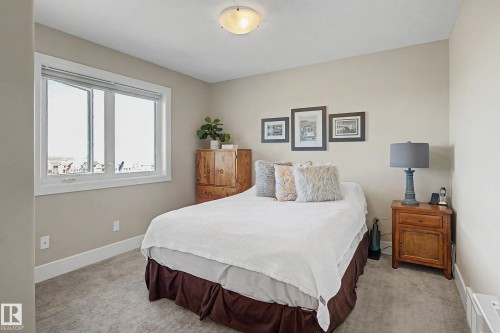 Carpeted room featuring a large window with white trim, light neutral wall paint, and a semi-flush mount ceiling light fixture - 2086 Redtail Common, Edmonton, AB - Indoor Photo Showing Bedroom
