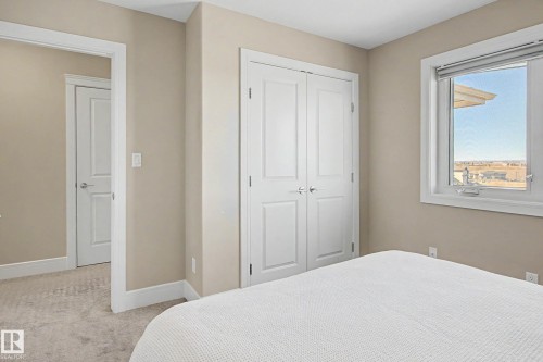 Bedroom featuring neutral-toned walls, white trim, and a double-door closet with polished chrome hardware - 2086 Redtail Common, Edmonton, AB - Indoor Photo Showing Bedroom