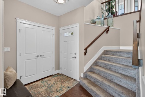 Entryway featuring wood-finish flooring, a white paneled front door with decorative glass inserts, and a built-in double-door closet - 2086 Redtail Common, Edmonton, AB - Indoor Photo Showing Other Room