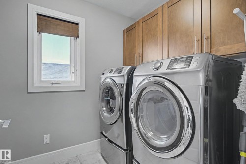 Laundry area featuring wood cabinetry, a white framed window, and light-toned flooring - 2086 Redtail Common, Edmonton, AB - Indoor Photo Showing Laundry Room