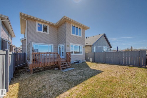 Rear exterior featuring a wooden deck with railing, dual-pane windows, and a sliding glass door - 2086 Redtail Common, Edmonton, AB - Outdoor