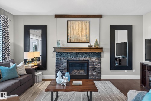 Living area featuring a stone-clad fireplace with a wood mantel - 2086 Redtail Common, Edmonton, AB - Indoor Photo Showing Living Room With Fireplace