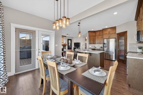 Dining area featuring wood-finish flooring and a multi-pendant linear chandelier - 2086 Redtail Common, Edmonton, AB - Indoor Photo Showing Dining Room