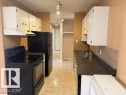 The kitchen features white cabinetry, a black refrigerator, a black range, a double basin sink, and tile backsplash - 201 10811 115 Street, Edmonton, AB  - Indoor Photo Showing Kitchen With Double Sink 