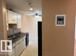The kitchen features white cabinetry, a double basin sink, and a black dishwasher - 