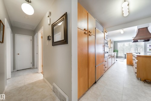 Galley-style kitchen featuring light wood cabinetry, integrated appliances, and a custom range hood - 10231 46 Street, Edmonton, AB - Indoor