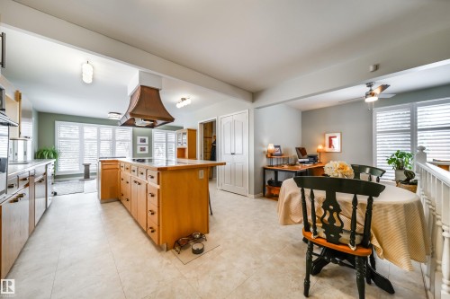 Eat-in kitchen featuring light wood cabinetry, a large center island with cooktop, a copper-finish range hood, and tile flooring - 10231 46 Street, Edmonton, AB - Indoor