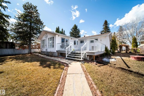 White siding exterior featuring a multi-level deck with glass panel railing and integrated steps, a sunroom with multiple windows, and an established pathway - 10231 46 Street, Edmonton, AB - Outdoor With Deck Patio Veranda