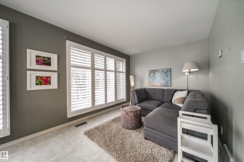 Living area featuring light-toned flooring, plantation shutters, and painted walls - 10231 46 Street, Edmonton, AB - Indoor Photo Showing Living Room