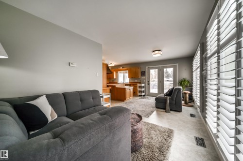 Expansive living area featuring light gray wall paint, large windows with plantation shutters, light-toned flooring, and a clear line of sight to the kitchen - 10231 46 Street, Edmonton, AB - Indoor Photo Showing Living Room