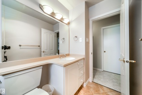 Bathroom featuring an integrated vanity with a built-in sink, an expansive wall-mounted mirror, and a three-light fixture - 10231 46 Street, Edmonton, AB - Indoor Photo Showing Bathroom