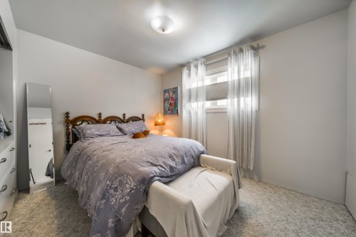 Carpeted room with a double window featuring blinds and sheer curtains - 10231 46 Street, Edmonton, AB - Indoor Photo Showing Bedroom