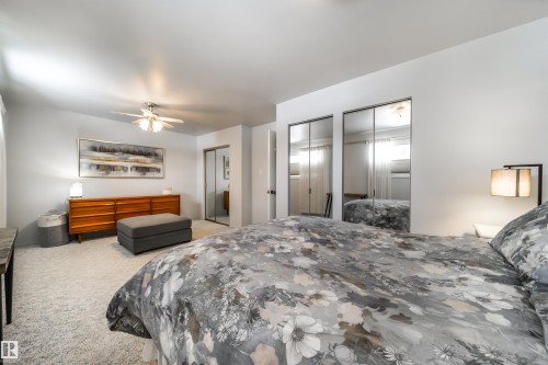 Bedroom featuring light-colored carpeting, a ceiling fan with integrated lighting, and two sets of mirrored closet doors - 10231 46 Street, Edmonton, AB - Indoor Photo Showing Bedroom