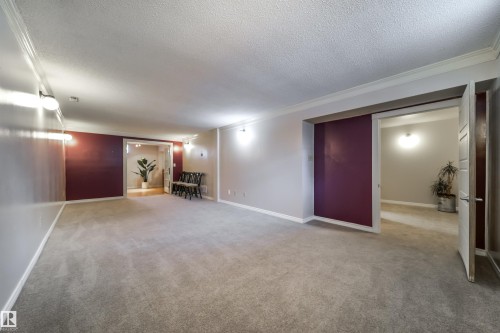 Spacious interior room featuring light-toned carpet flooring, neutral wall tones, and crown molding - 10231 46 Street, Edmonton, AB - Indoor Photo Showing Other Room