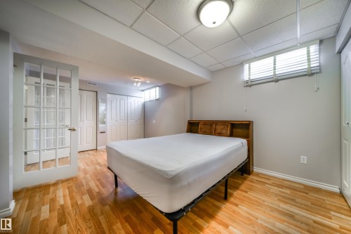 Bedroom with wood-finish flooring, two sets of white bi-fold closet doors, and an overhead lighting fixture - 10231 46 Street, Edmonton, AB - Indoor Photo Showing Other Room