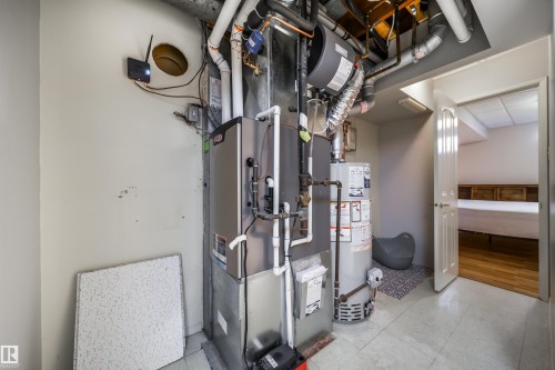 Utility area with a visible furnace and water heater, featuring exposed ductwork and piping - 10231 46 Street, Edmonton, AB - Indoor Photo Showing Basement