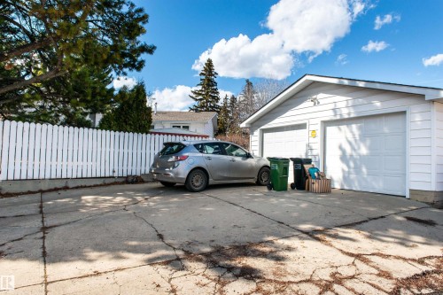 Detached two-car garage with white vinyl siding, two panel garage doors, and a white picket fence bordering the property - 10231 46 Street, Edmonton, AB - Outdoor