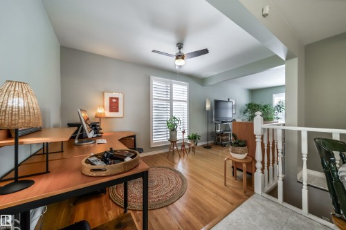 Open concept living space featuring wood-finish flooring, white plantation shutters, and a ceiling fan - 10231 46 Street, Edmonton, AB - Indoor
