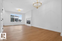 Spacious room featuring wood-finish flooring, a modern linear fireplace with a textured surround, and a large window providing natural illumination - 