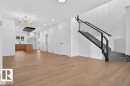 Open concept living space featuring wood-finish flooring, a modern staircase with glass railing and black handrails, recessed lighting, and a contemporary gold chandelier - 55 Rosa Crescent, St. Albert, AB  - Indoor Photo Showing Other Room 