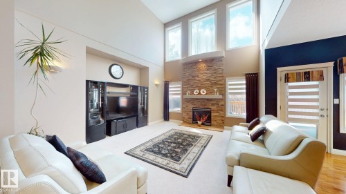 The living space features vaulted ceilings, a prominent fireplace with a stone surround, and large windows that provide abundant natural light - 613 Todd Link, Edmonton, AB - Indoor Photo Showing Living Room With Fireplace