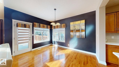 This interior space features hardwood flooring, a contrasting accent wall, and multiple windows providing natural light - 613 Todd Link, Edmonton, AB - Indoor Photo Showing Other Room