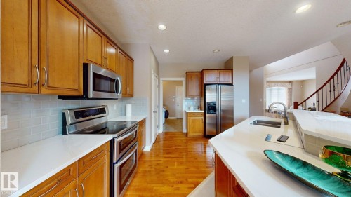 The kitchen features light wood cabinetry, stainless steel appliances, white countertops, and hardwood floors - 613 Todd Link, Edmonton, AB - Indoor Photo Showing Kitchen With Double Sink