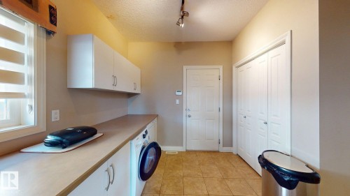 This utility room features neutral wall paint, tiled flooring, a window with horizontal blinds, and overhead track lighting - 613 Todd Link, Edmonton, AB - Indoor