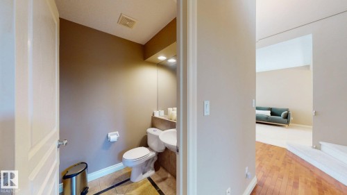 A well-appointed powder room featuring a toilet, sink, and mirror, with tiled flooring and recessed lighting - 613 Todd Link, Edmonton, AB - Indoor Photo Showing Bathroom
