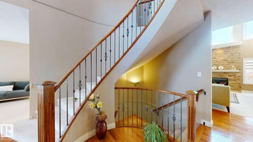 The property features a curved staircase with wooden handrails and wrought iron balusters, leading to an upper level - 613 Todd Link, Edmonton, AB - Indoor Photo Showing Other Room