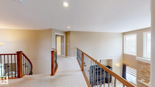 The property features an open landing area with carpeted floors, recessed lighting, and wooden railings with wrought iron accents - 613 Todd Link, Edmonton, AB - Indoor Photo Showing Other Room