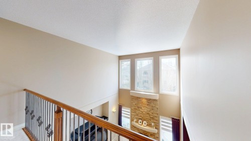 The property features a multi-story interior with a wooden handrail and metal balusters - 613 Todd Link, Edmonton, AB - Indoor Photo Showing Other Room