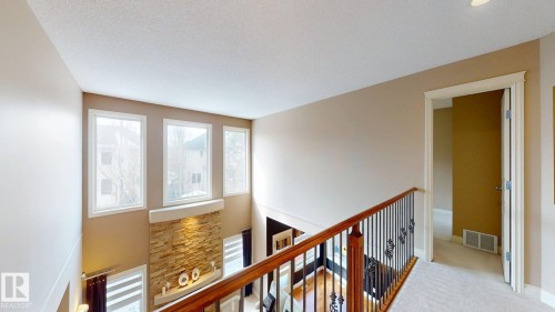 Overlooking the living area, this space features a decorative railing, carpeted flooring, and a doorway leading to an interior room - 613 Todd Link, Edmonton, AB - Indoor Photo Showing Other Room