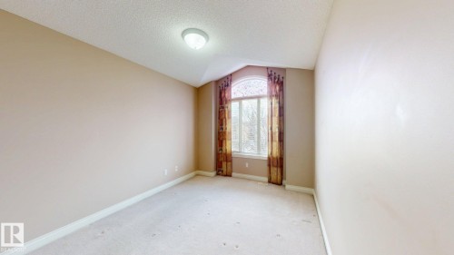 This room features a window with an arched transom, carpeted flooring, and a ceiling light fixture - 613 Todd Link, Edmonton, AB - Indoor Photo Showing Other Room