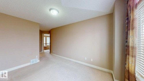 This room features neutral-toned walls, carpeted flooring, and a window with blinds and patterned curtains - 613 Todd Link, Edmonton, AB - Indoor Photo Showing Other Room