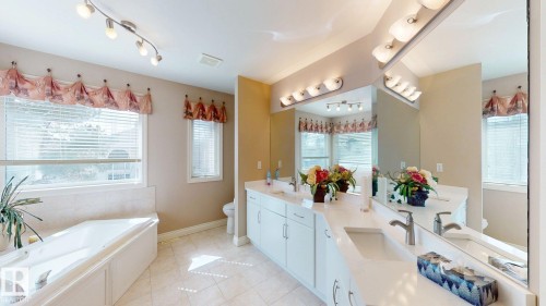 The bathroom features a spacious bathtub, a dual vanity with undermount sinks, and a large mirror - 613 Todd Link, Edmonton, AB - Indoor Photo Showing Bathroom