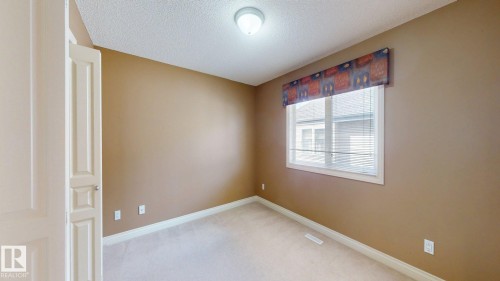 The room features neutral-toned walls, carpeted flooring, and a window with blinds and a decorative valance - 613 Todd Link, Edmonton, AB - Indoor Photo Showing Other Room